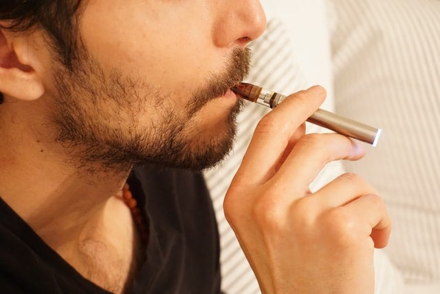 Young man smoking from a thc vape.