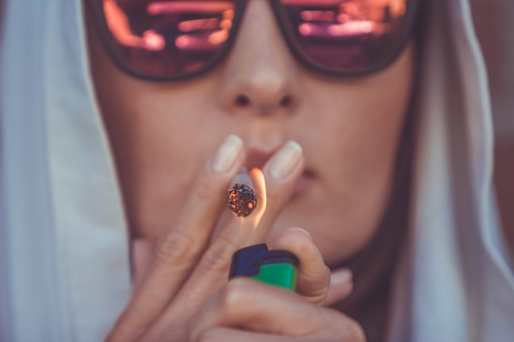 Young man with sunglasses smoking a joint.