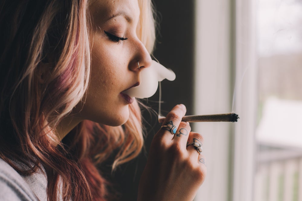 Young lady with died blonde and red hair smoking a joint. 