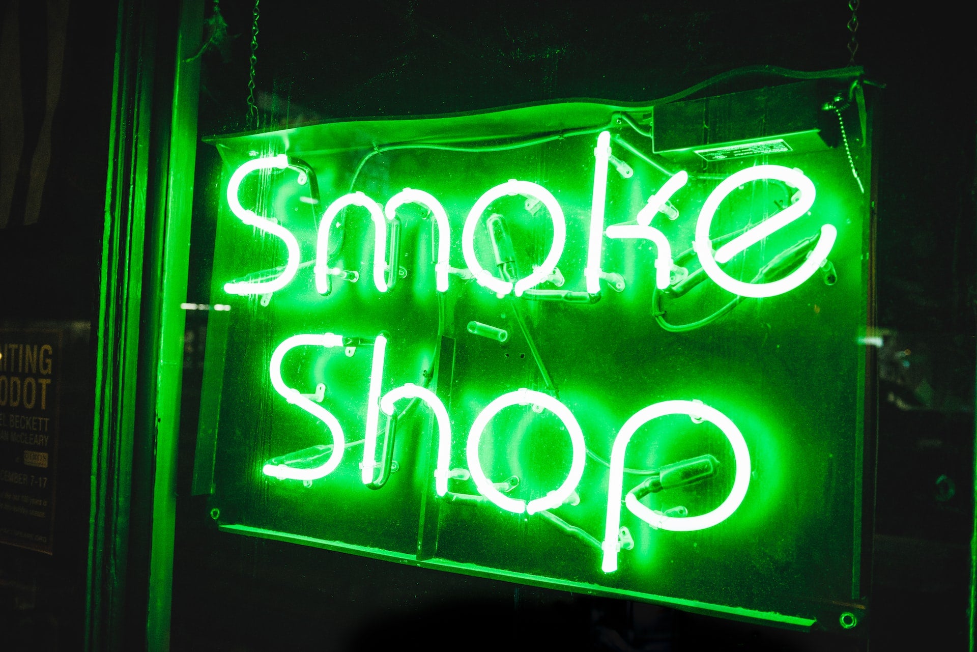 Green neon sign that reads smoke shop.