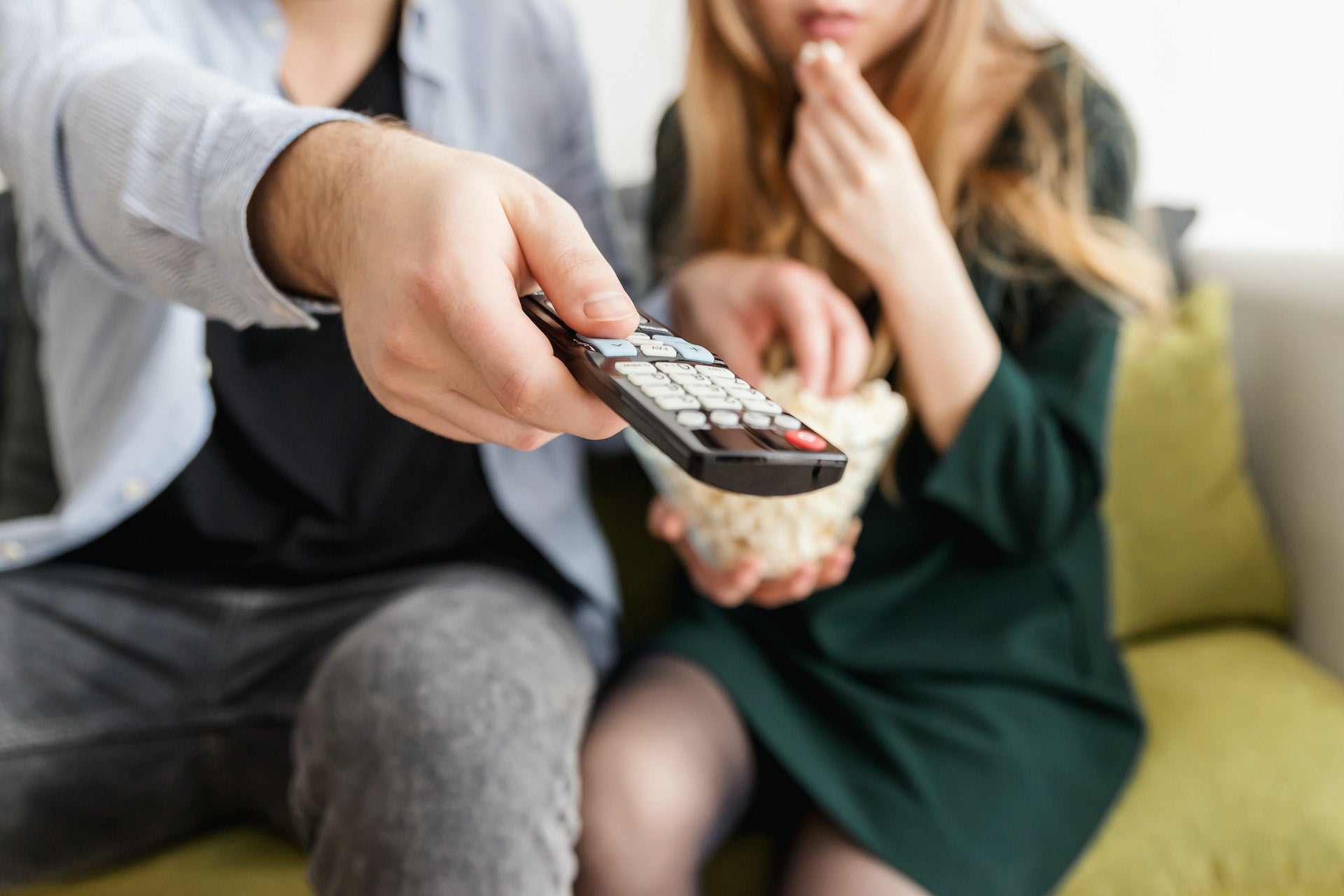 Couple watching a movie together. Man has remote control in his hand.